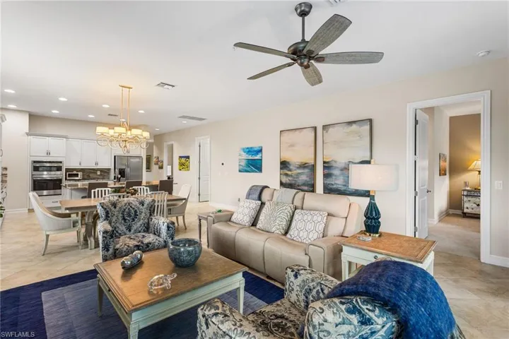 Living area with light tile patterned floors, ceiling fan, and a chandelier
