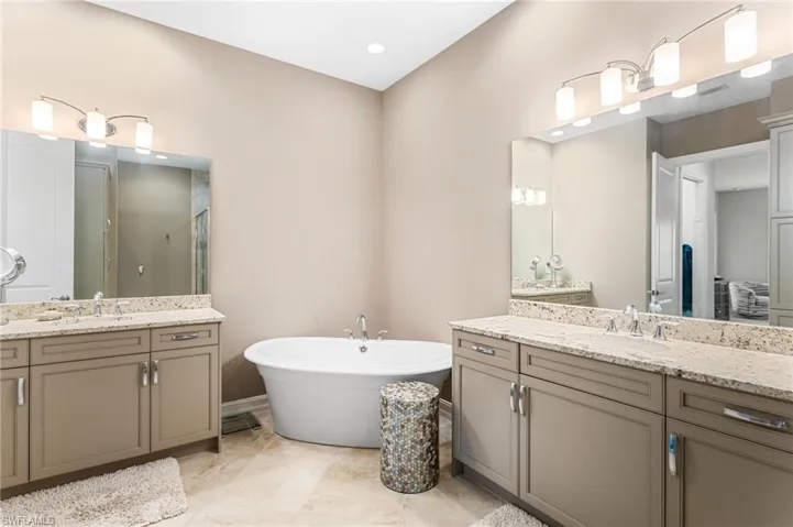 Full bathroom with two vanities, a freestanding bath, and a stall shower