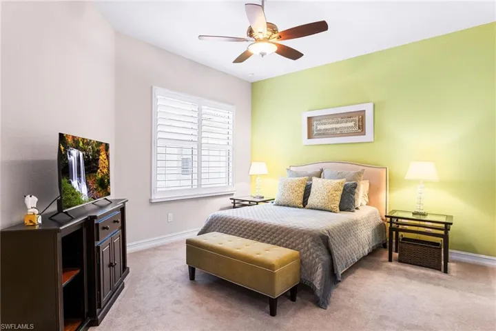 Bedroom with light colored carpet and a ceiling fan