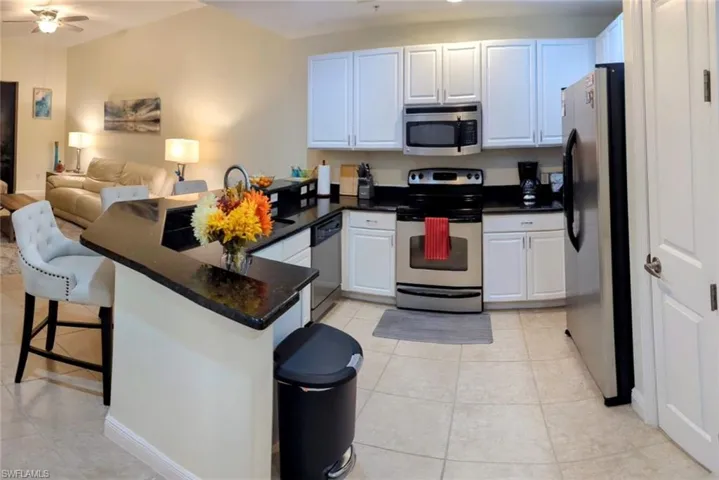 Kitchen featuring a breakfast bar, white cabinetry, kitchen peninsula, stainless steel appliances, and ceiling fan