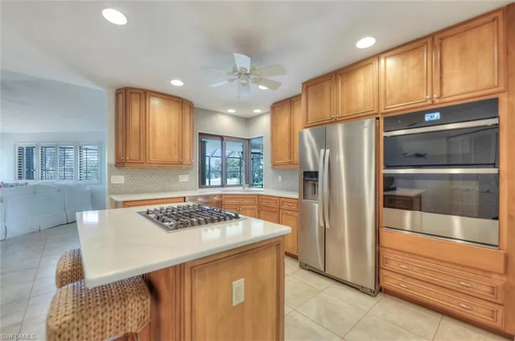 Kitchen featuring recessed lighting, ceiling fan, appliances with stainless steel finishes, a breakfast bar area, and a kitchen island