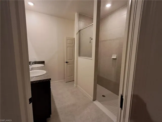 Full bathroom with walk in shower, double vanity, light tile patterned flooring, and recessed lighting
