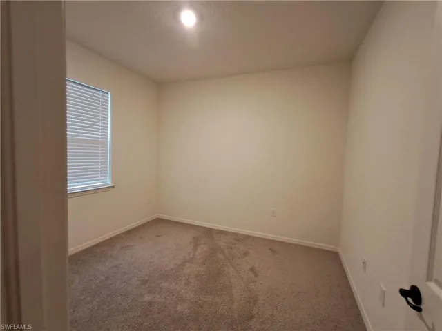 Carpeted spare room featuring baseboards