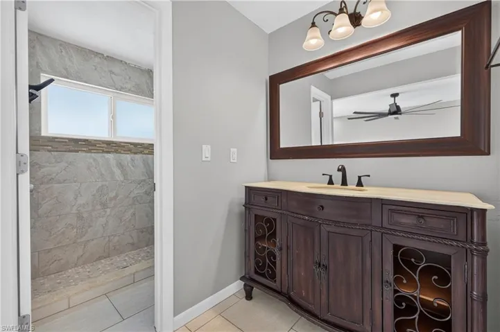 Custom vanity with a light-colored countertop, framed mirror, and three-light fixture