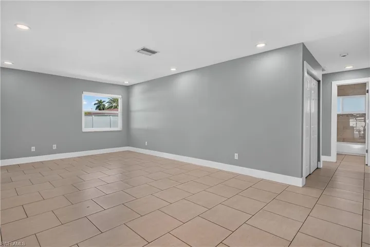 Recessed ceiling lighting, neutral tile flooring, window with exterior landscape, and a bi-fold closet door