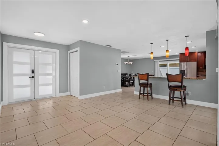 Neutral tile flooring, double entry doors with frosted glass panels, built-in closet, kitchen pass-through with granite countertop, and recessed ceiling lighting