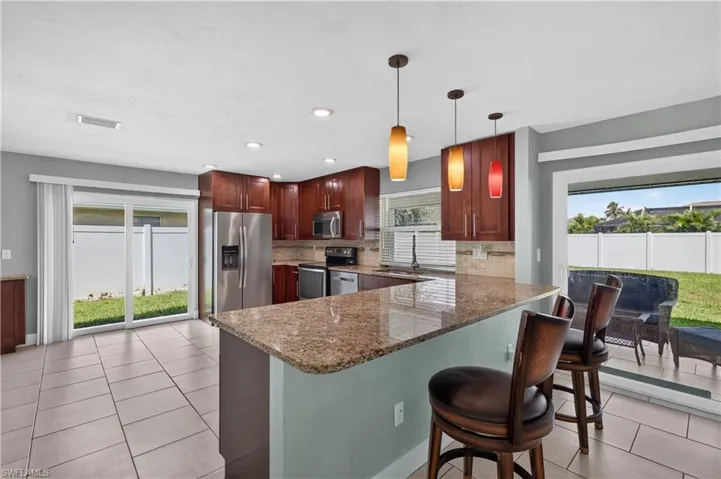 Kitchen with recessed lighting, wood-finish cabinetry, a large island with countertop seating, and sliding glass doors