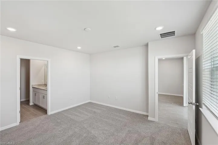 Unfurnished bedroom featuring light colored carpet, baseboards, visible vents, and recessed lighting