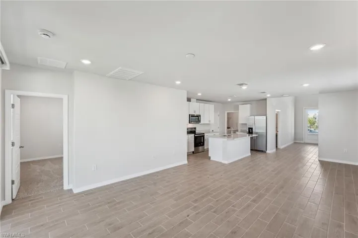 Unfurnished living room with visible vents, baseboards, light wood-type flooring, and recessed lighting