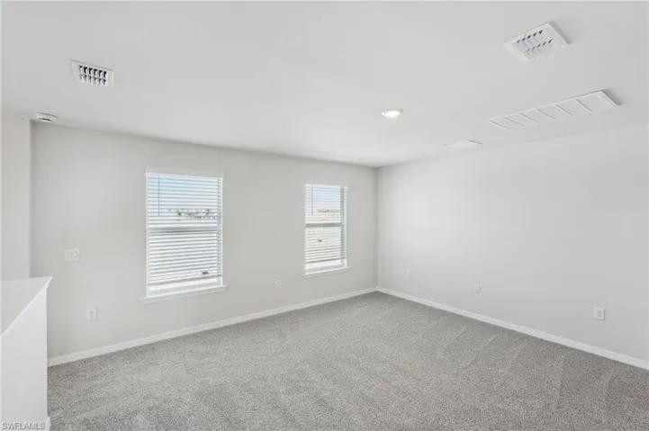 Carpeted spare room with visible vents and baseboards
