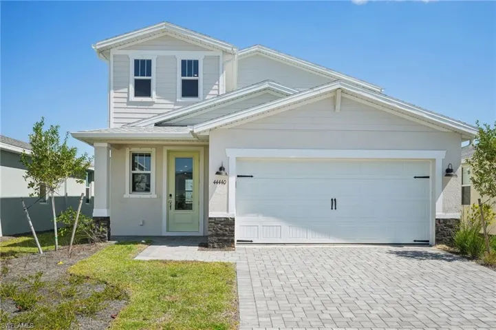 View of front facade with stone siding, a garage, decorative driveway, and stucco siding