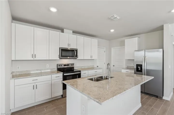 Kitchen featuring wood finish floors, white cabinetry, visible vents, appliances with stainless steel finishes, and a sink
