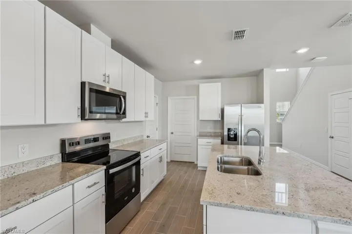 Kitchen with a sink, visible vents, appliances with stainless steel finishes, and a center island with sink