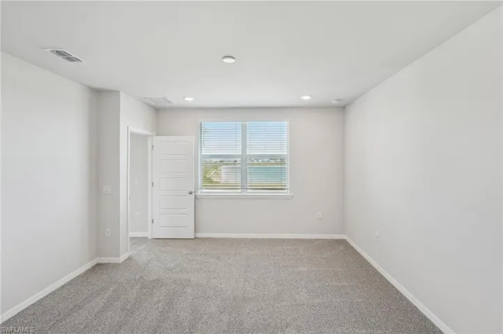 Spare room featuring light carpet, visible vents, and baseboards