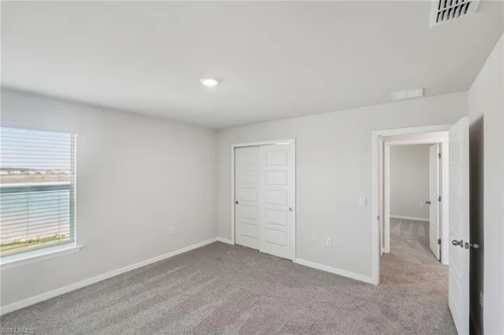 Unfurnished bedroom featuring a closet, baseboards, carpet, and visible vents