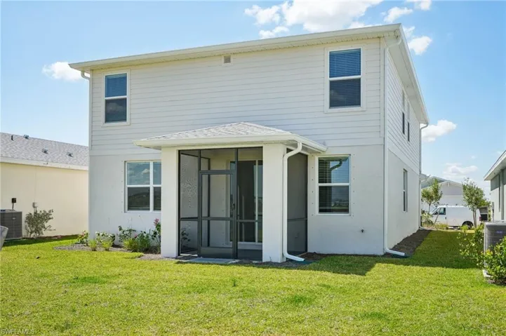 Rear view of property featuring a yard, a sunroom, and central air condition unit