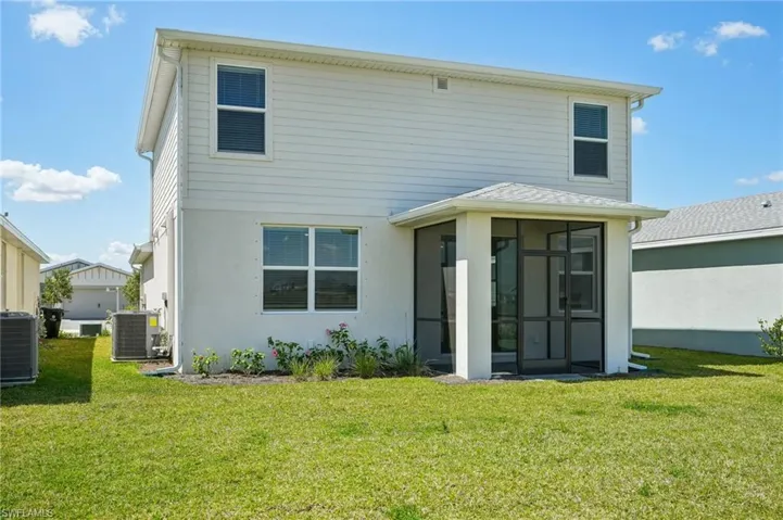 Rear view of house featuring cooling unit, a lawn, and a sunroom