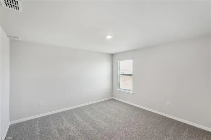 Spare room featuring carpet flooring, baseboards, and visible vents