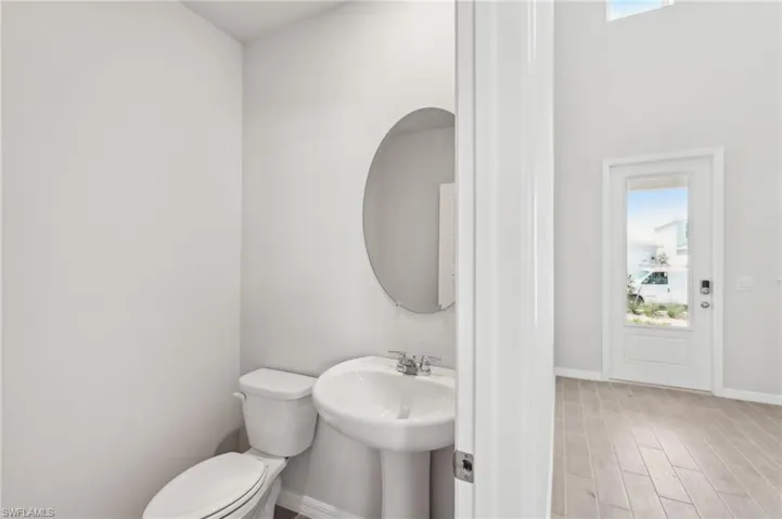 Bathroom featuring toilet, wood finished floors, a sink, and baseboards
