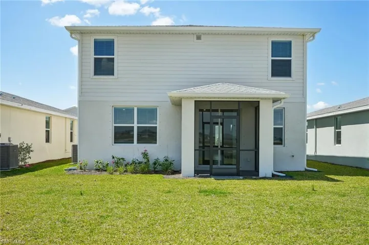 Back of house with a sunroom, a yard, cooling unit, and stucco siding