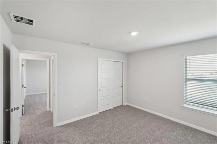 Unfurnished bedroom with carpet, visible vents, a closet, and baseboards