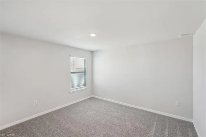 Carpeted spare room featuring baseboards