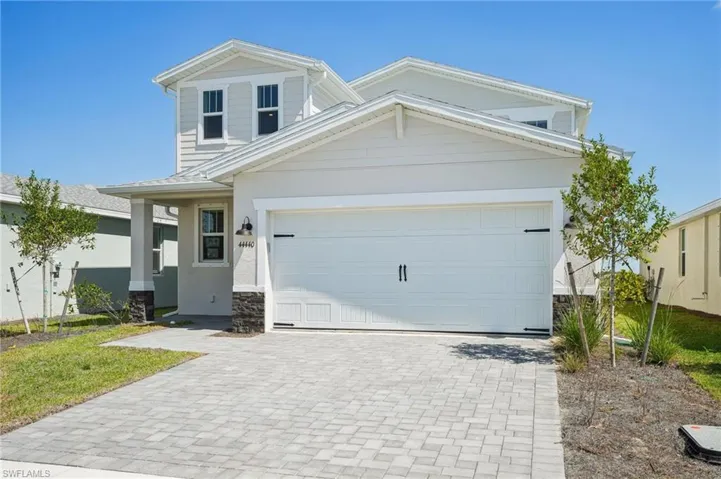 View of front of home featuring a garage, stucco siding, stone siding, and decorative driveway