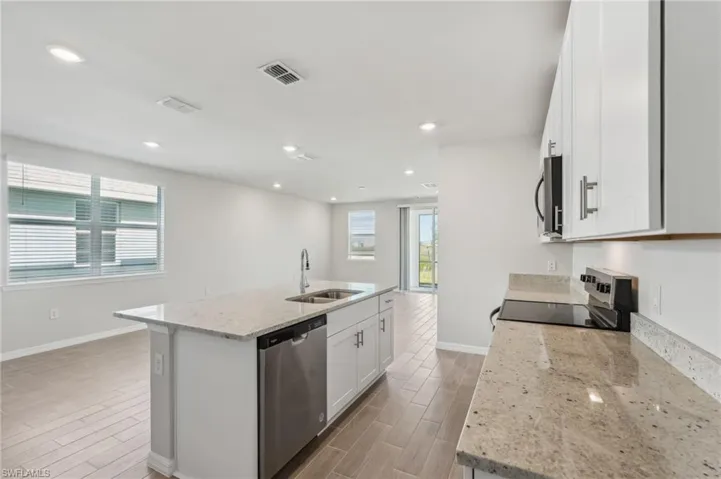 Kitchen with baseboards, visible vents, stainless steel appliances, light wood finished floors, and a sink