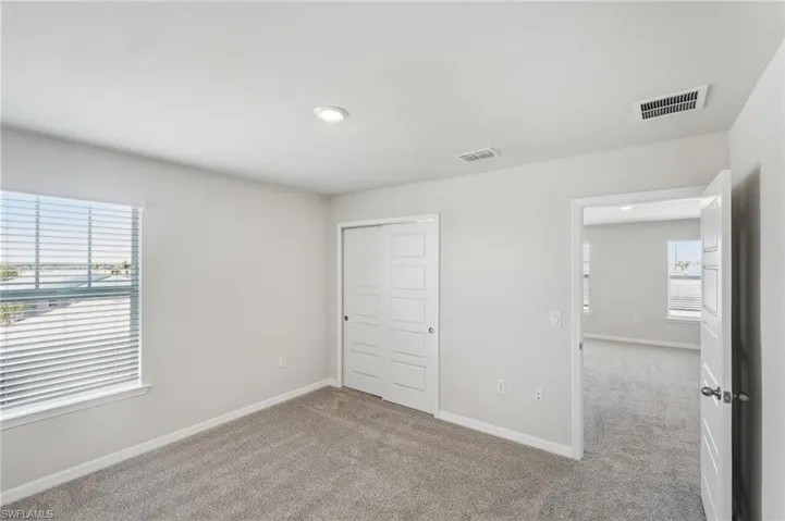 Unfurnished bedroom featuring visible vents, baseboards, and carpet