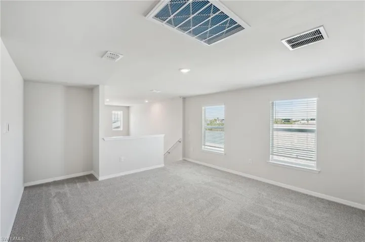 Carpeted spare room featuring recessed lighting, visible vents, and baseboards