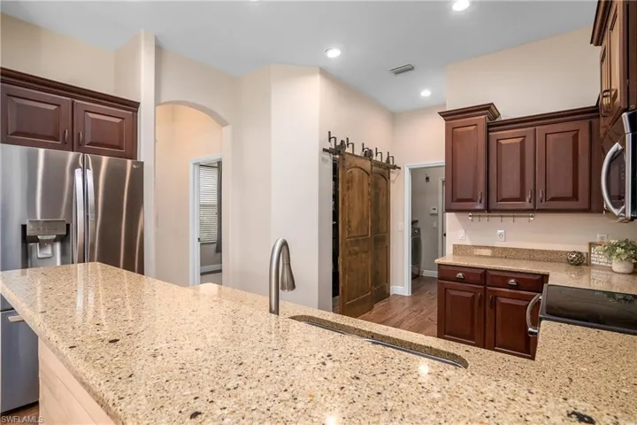 Kitchen with granite counters, plank tile flooring, appliances with stainless steel finishes