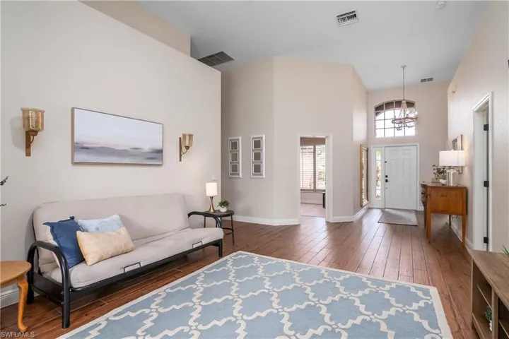 Living room featuring a notable chandelier, a towering ceiling, and dark hardwood / wood-style flooring