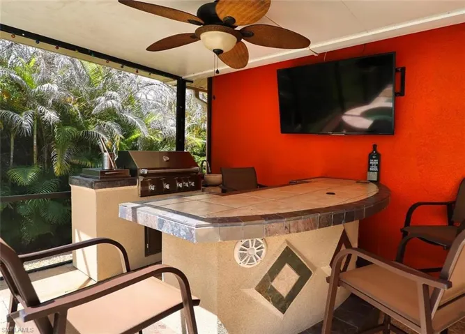 Bar featuring ceiling fan and tile countertops