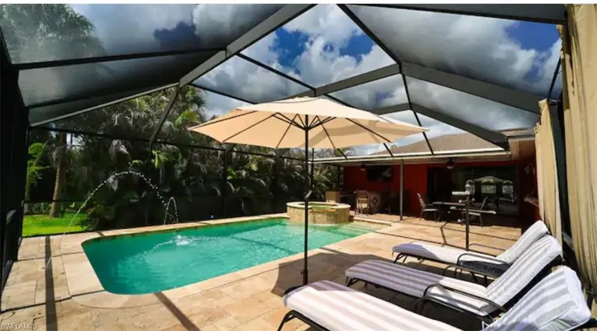 View of pool with a patio, glass enclosure, and an in ground hot tub