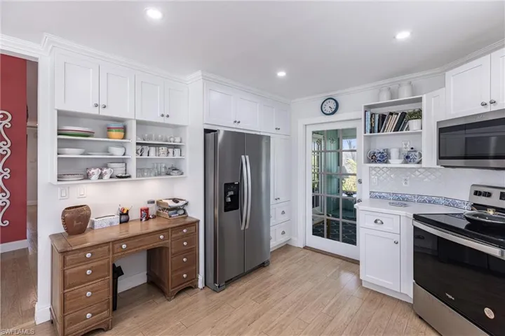 Kitchen featuring white cabinets, open shelves, appliances with stainless steel finishes, and light wood-type flooring