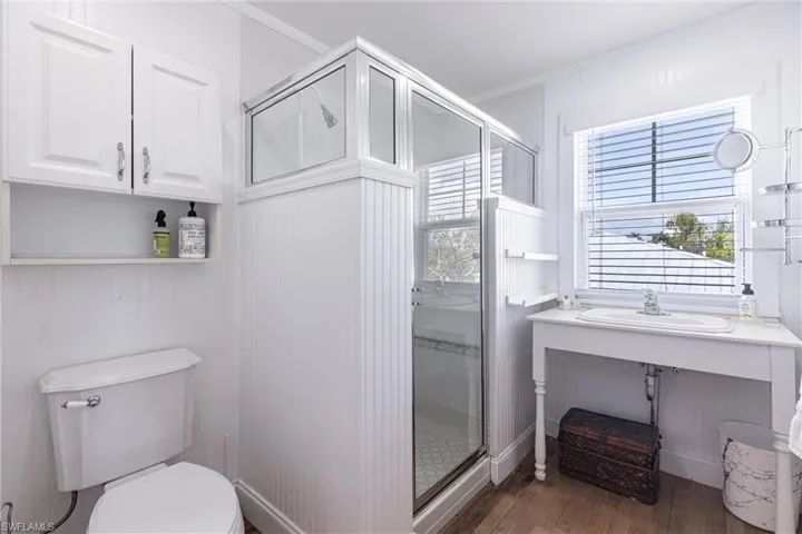 Full bathroom with toilet, a sink, a shower stall, and wood finished floors