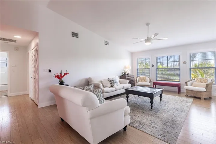 Living room with a ceiling fan, wood finished floors, and visible vents
