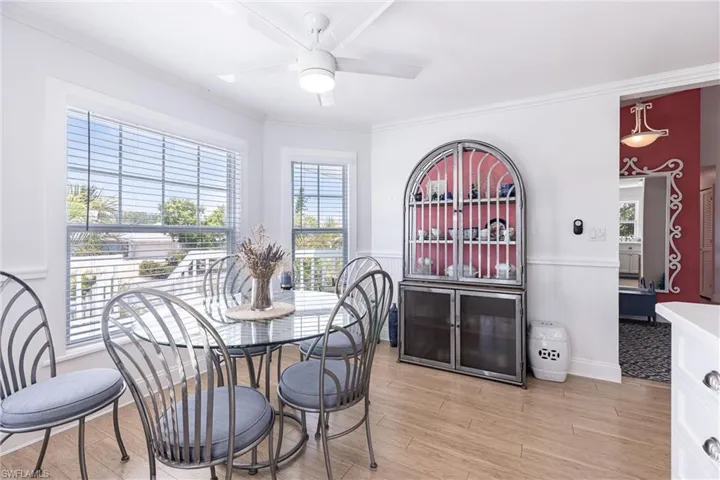 Dining room with plenty of natural light, a ceiling fan, wainscoting, and crown molding