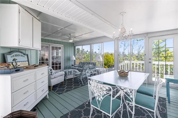 Sunroom with beam ceiling, a notable chandelier, and a wealth of natural light
