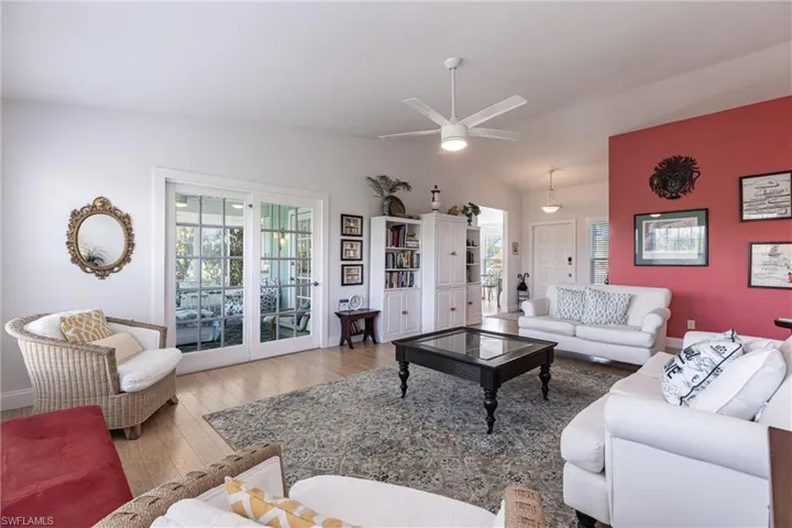 Living area with a ceiling fan, baseboards, vaulted ceiling, and wood finished floors