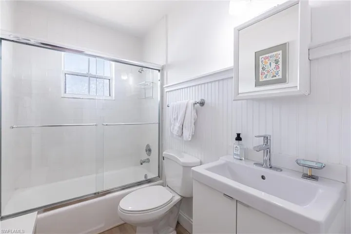 Bathroom with a sink, combined bath / shower with glass door, and toilet
