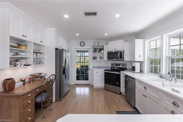 Kitchen featuring visible vents, open shelves, a sink, white cabinets, and stainless steel appliances