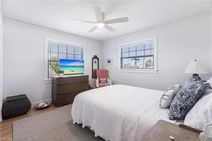 Bedroom with crown molding, baseboards, ceiling fan, and wood finished floors