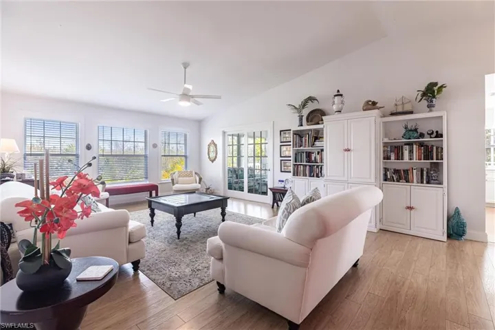 Living room featuring a ceiling fan, lofted ceiling, and light wood finished floors