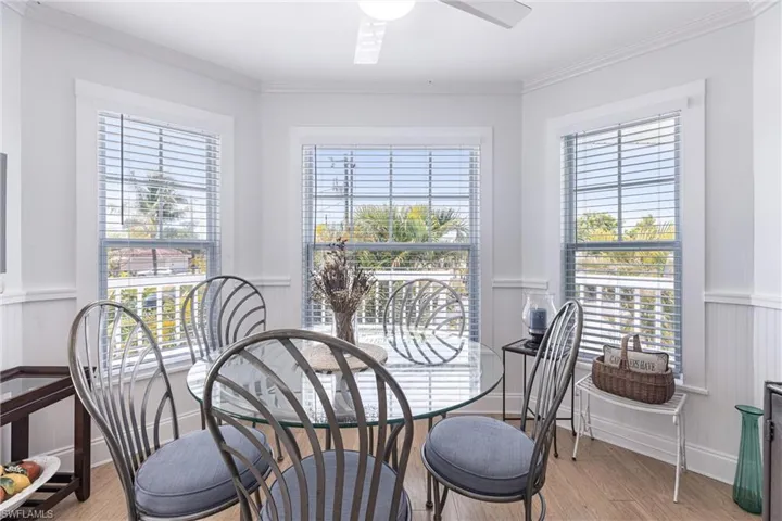 Dining area featuring crown molding, a ceiling fan, light wood finished floors, and wainscoting
