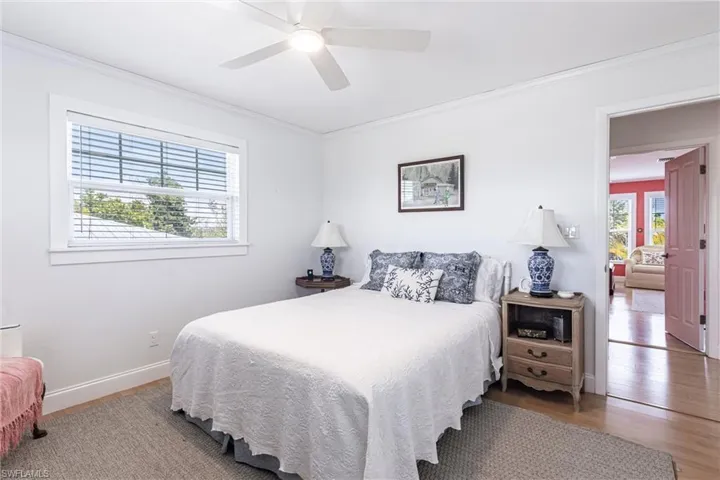 Bedroom with a ceiling fan, baseboards, ornamental molding, and wood finished floors