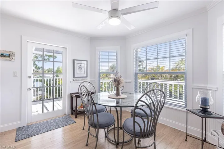 Dining room featuring a ceiling fan, ornamental molding, light wood finished floors, and a wainscoted wall