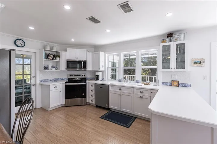 Kitchen with visible vents, open shelves, light countertops, appliances with stainless steel finishes, and backsplash