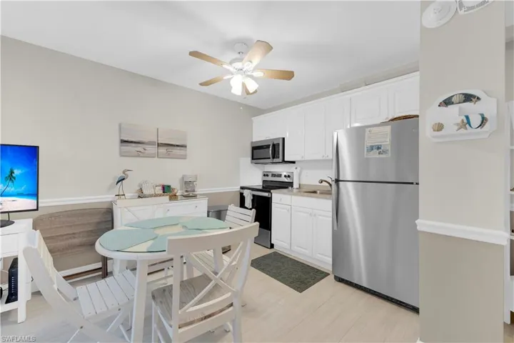 Kitchen with stainless steel appliances, white cabinetry, light countertops, and a ceiling fan