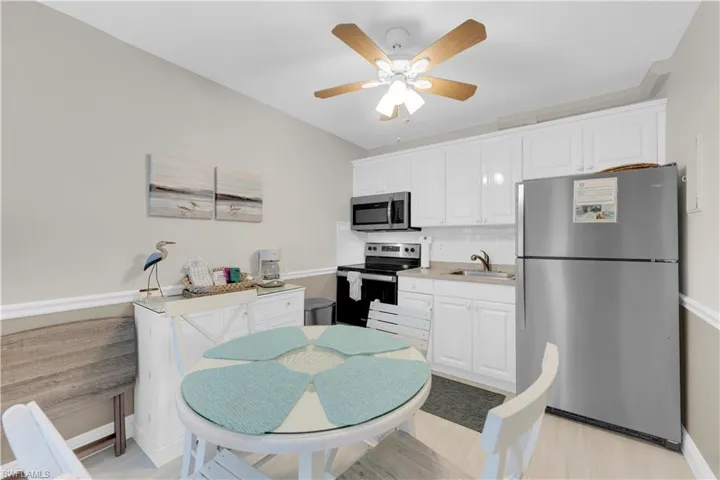 Kitchen featuring stainless steel appliances, light countertops, white cabinetry, backsplash, and ceiling fan